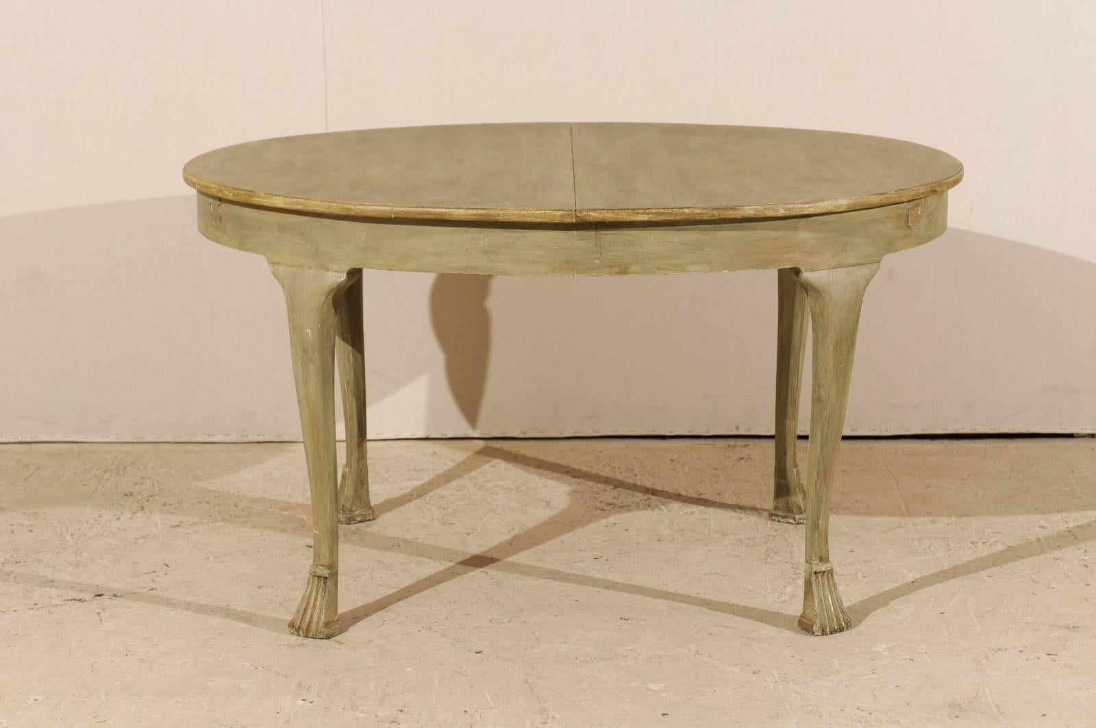 A European 19th century oval table. This painted wood table (circa 1880) is raised on four Spanish style feet and comes with two hideaways leaves. The table top separates in its center to give space for the leaves. The table of a light grey green
