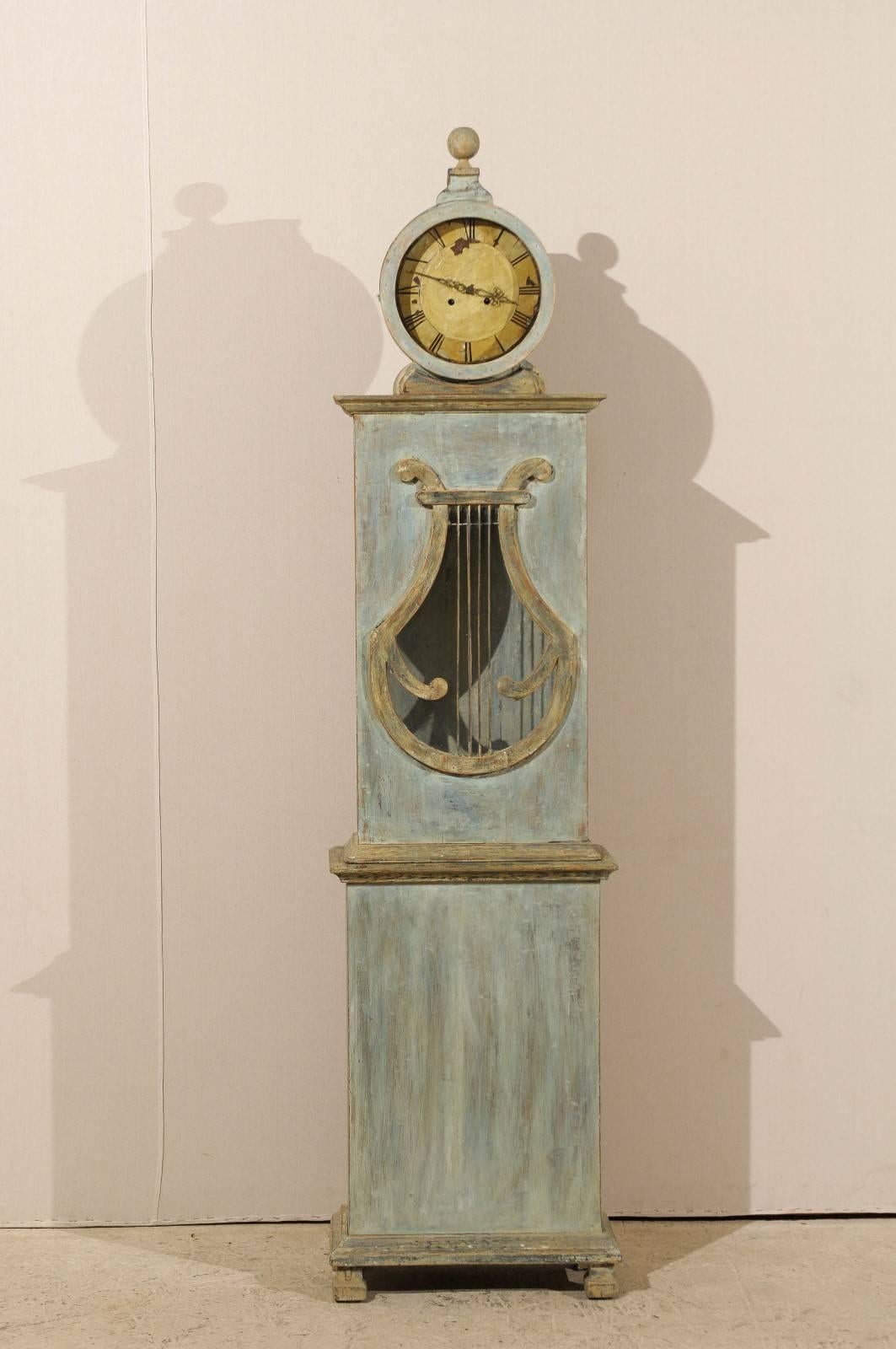 A 19th century Swedish clock. This Swedish clock features a wonderful eye catching lyre shaped motif in the otherwise rectangular belly, where you traditionally find a round opening. The round head is topped with a round finial and shelters a nicely