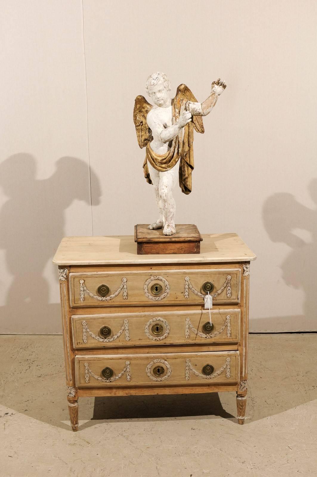 An Italian 18th century angel statue with nice aging. This carved wood table top statue of an angel features gilded wings and sash, wrapped around his shoulder and waist. The angel is raised on a square wooden base. Very nice detail execution on the