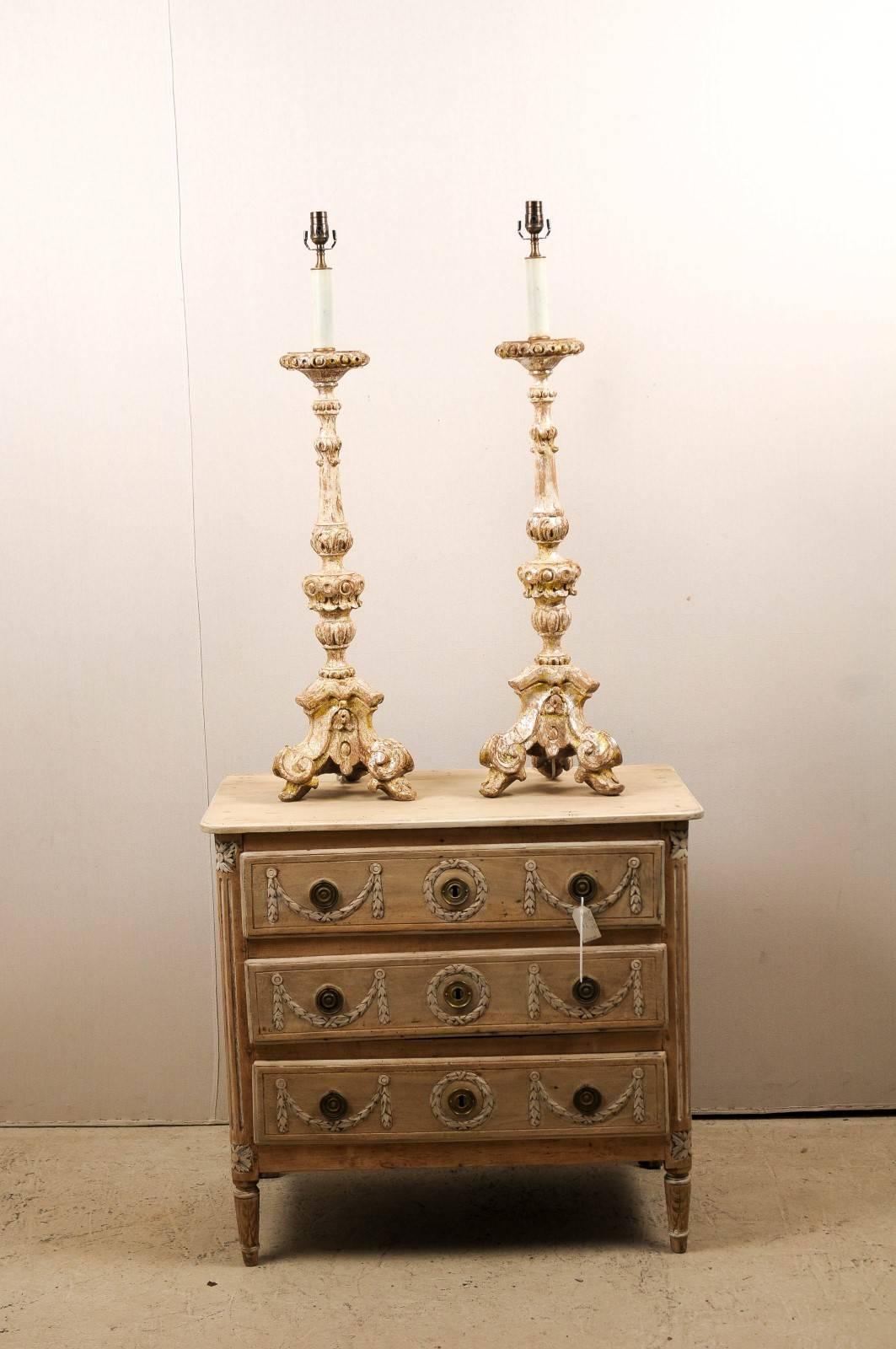 A pair of carved wood altar sticks from the 19th century made into table lamps. This exquisite pair of large size, tall Italian wooden table lamps features a nicely scraped finish with traces of silver gilding and yellow paint. The lamps have a