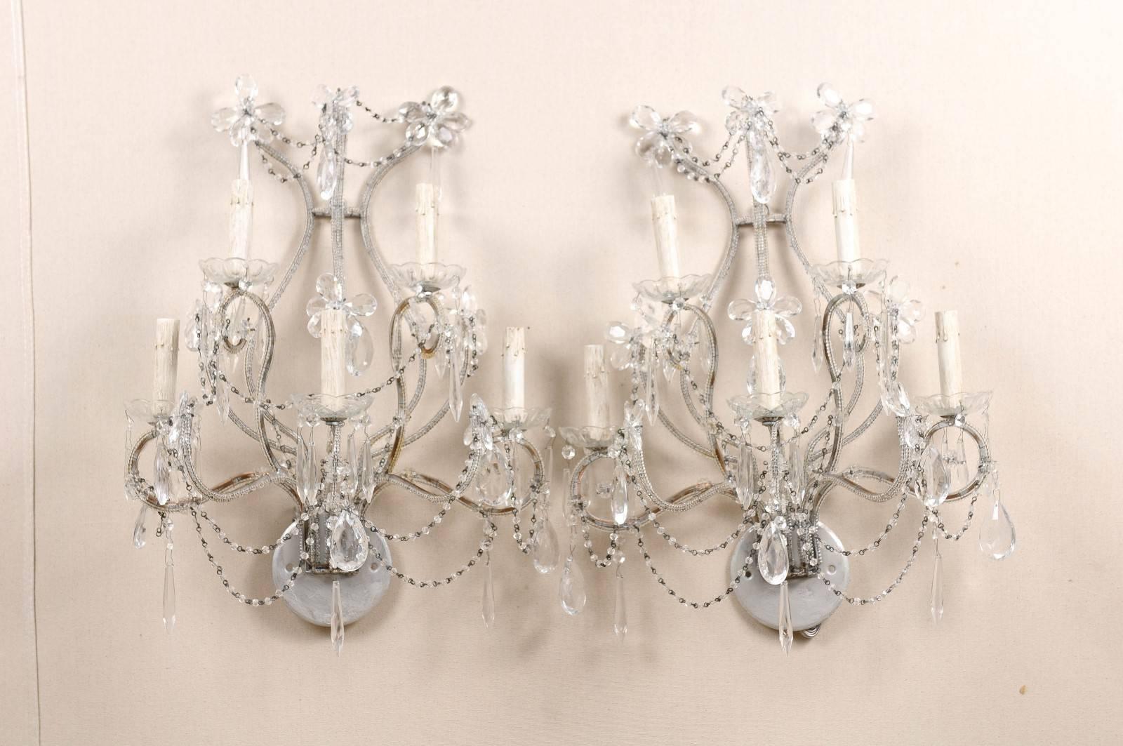 A pair of Italian crystal sconces. This pair of Italian crystal sconces from the mid-20th century features five lights with glass bobèches divided on two levels. The metal armature and backplate have been painted grey. Delicate beading, strands,
