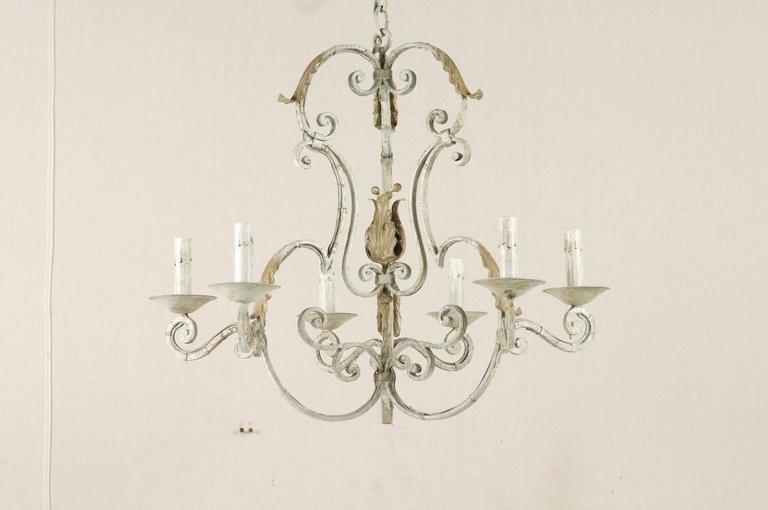 A French painted iron six-light chandelier. This vintage French chandelier is decorated with scrolls throughout. Also featured are decorative carved acanthus leaves towards the top and bottom of the piece. The overall color of this chandelier is a