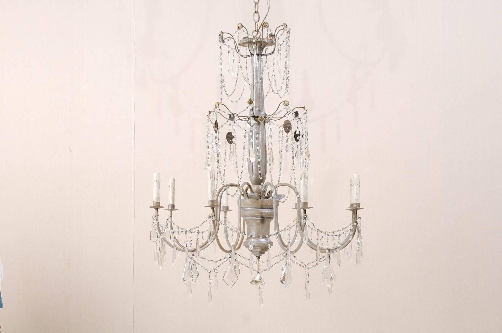 An Italian eight-light crystal chandelier with painted wood central column and metal swoop arms. This chandelier is a silver color with darker undertones. The central column on this chandelier is nicely fluted. There are floral motifs decorating