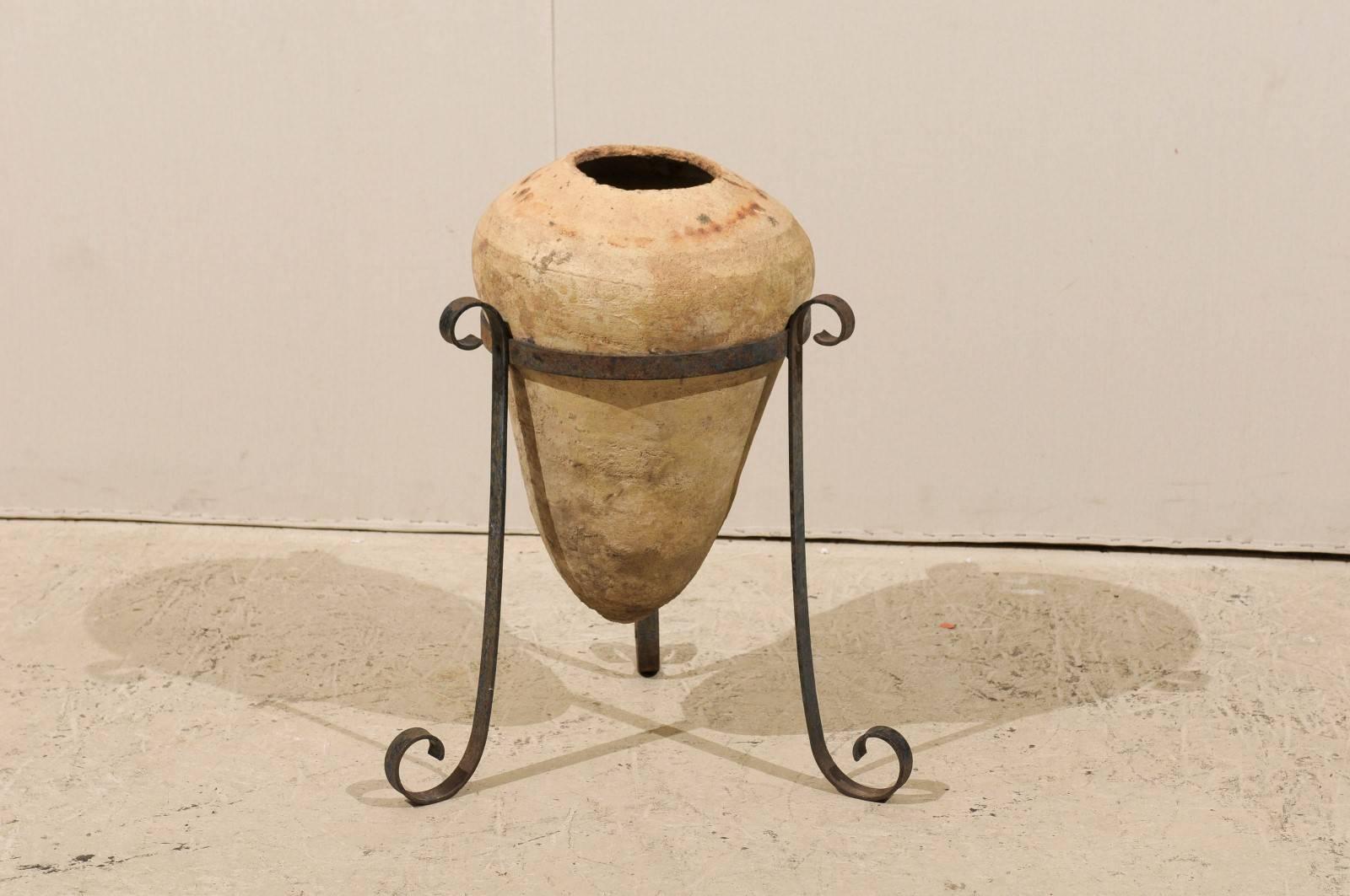 A clay Spanish colonial period jar from the 18th century. This jar is raised on a tripod custom-made metal stand. The finish is of a natural pale color.