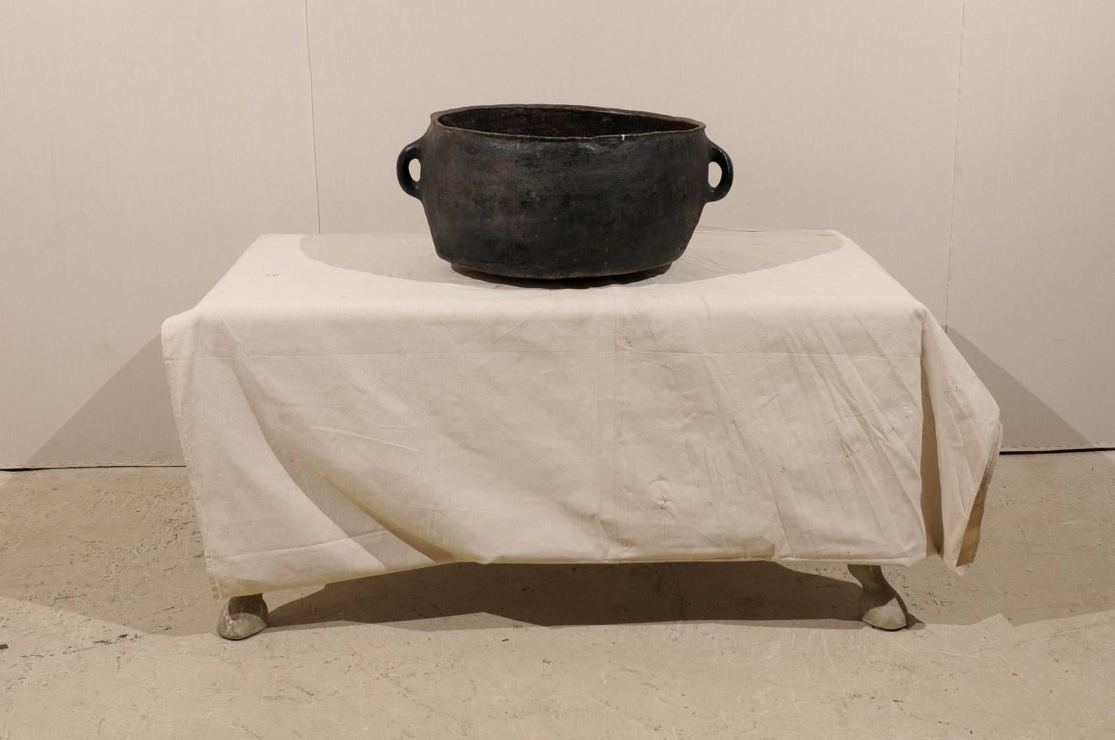 A Spanish Colonial cooking pot from the mid-19th century with wide mouth and two handles. This Spanish Colonial pot from Sacoj, Guatemala is made of clay. It is a deep black color. It was used to cook beans.
