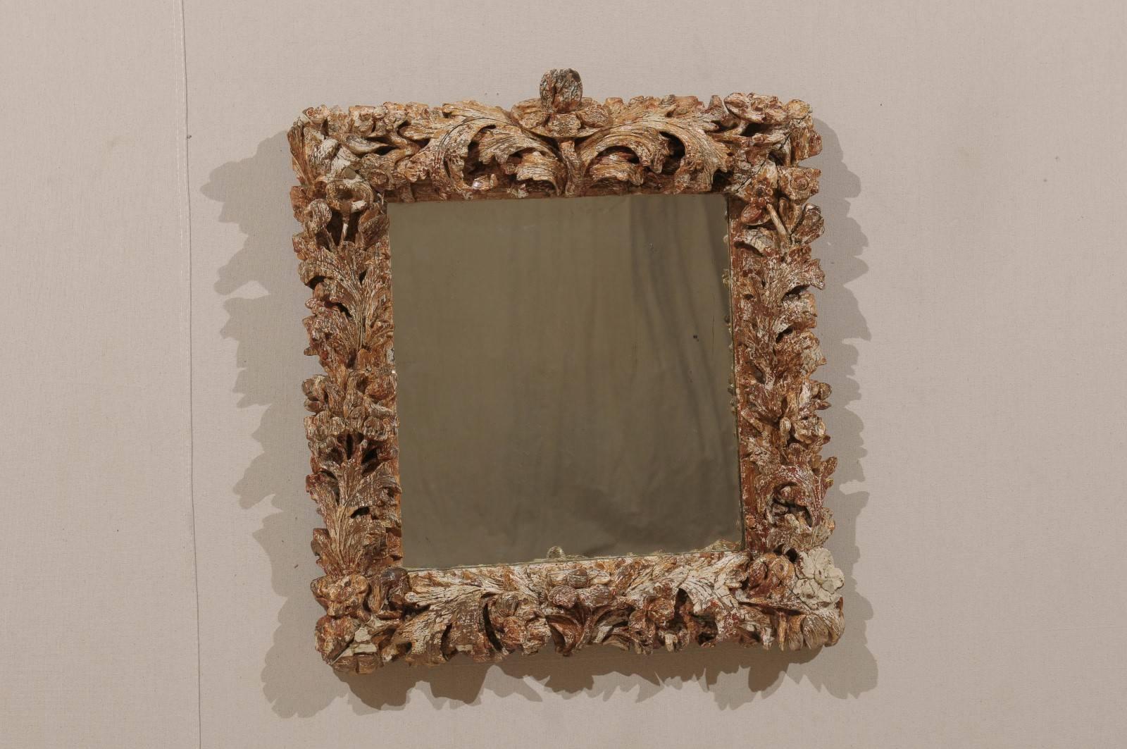 An Italian late 17th-early 18th century mirror. This exquisite Italian mirror features a richly carved surround with foliage motifs. This Italian mirror features traces of antique gilt over gesso. The overall color is brown with some traces of red