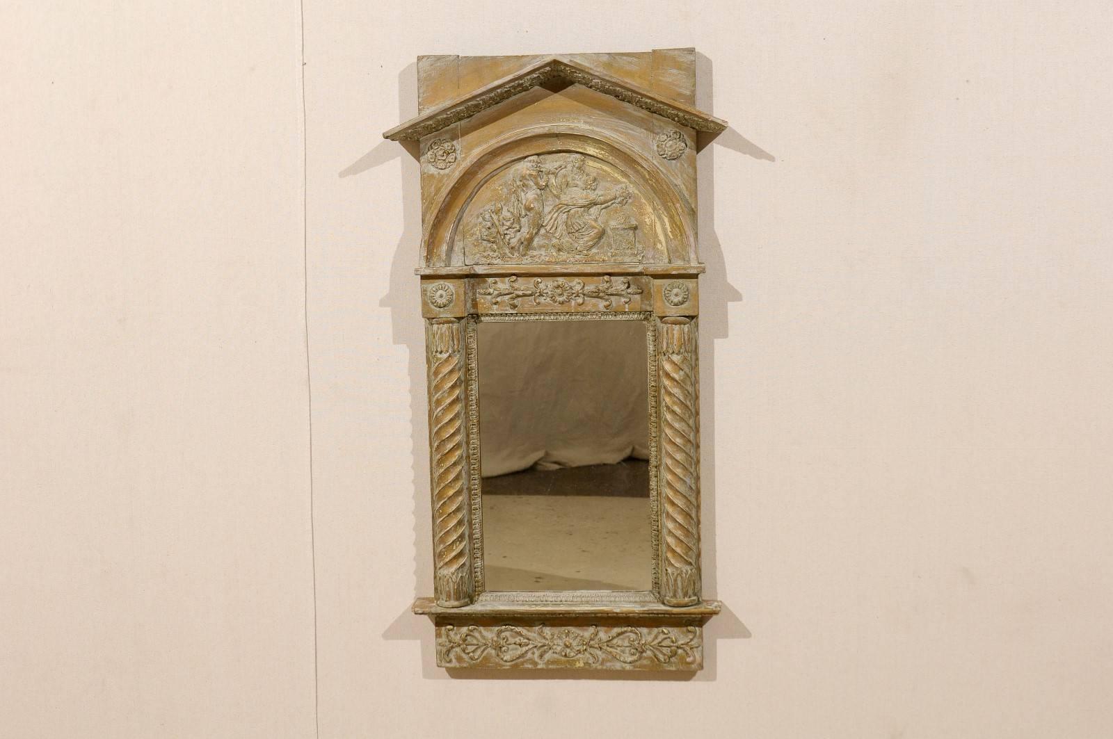 A Swedish wood carved mirror, circa 1820. This neoclassical Swedish mirror features a triangular molding at the crest, reminiscent of the triangular pediment of a Greco-Roman temple, under which the mythological characters carved in low-relief take