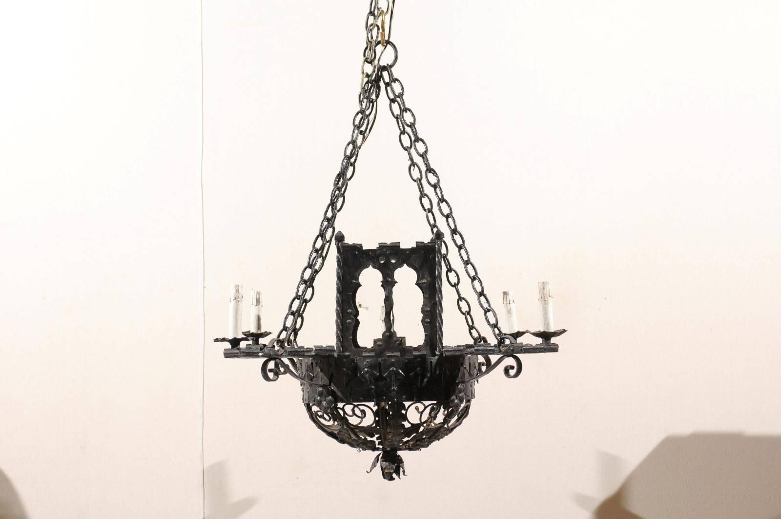 A pair of Italian vintage forged iron five-light chandeliers. These chandeliers from the mid 20th century feature a single light in the center surrounded by a rectangular structure, as well as one light at the end of each of the four straight arms.