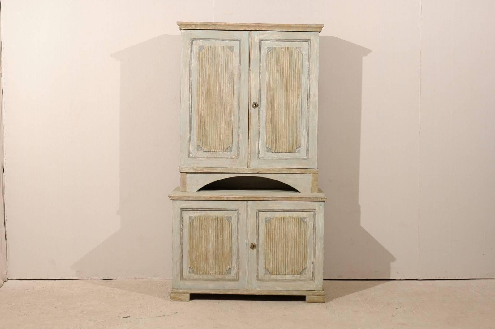A Swedish 19th century period Gustavian painted wood cabinet with receded doors and block feet. This Swedish cabinet features two doors in the upper section, opening to multiple inner shelves. An opened arched section separates the top from the