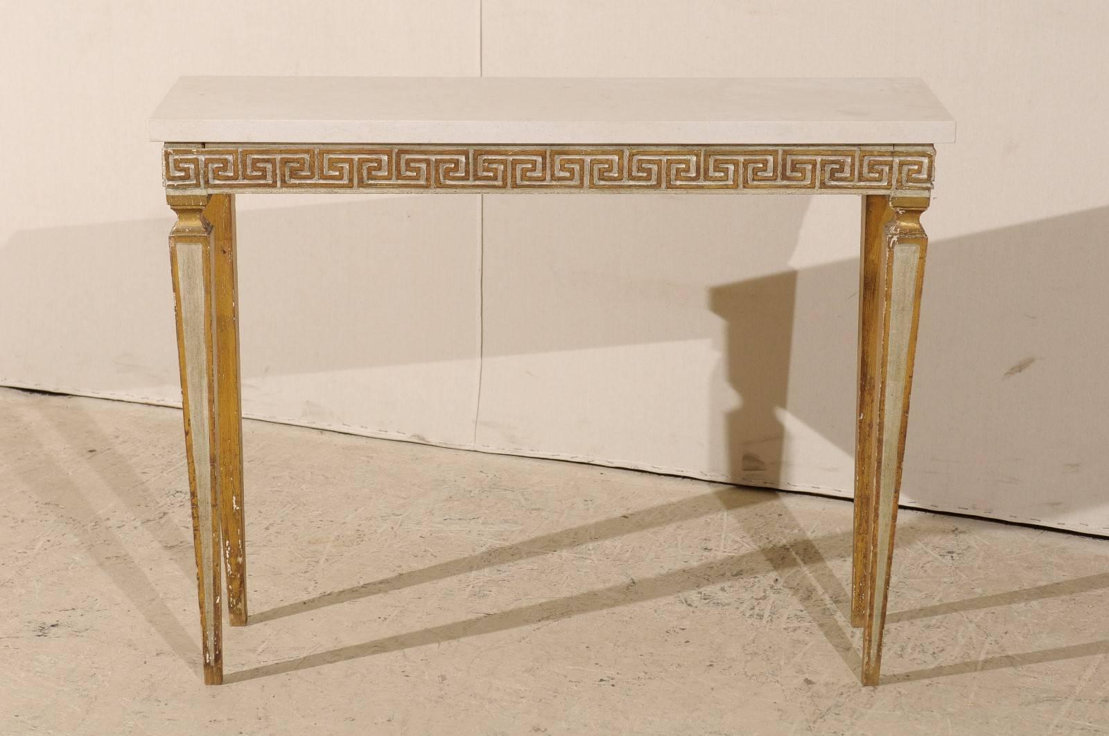 An Italian marble-top console table with Greek key motifs from the mid-20th century. This Italian console table is topped with white marble. This table also features a Greek key pattern on its skirt, to which four tapered legs are connected. This