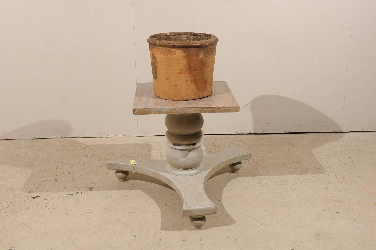 A Spanish aged clay pot from the 19th century. This Spanish clay pot features a spout at the base, great for draining. The general color is light brown color with some darker brown throughout.