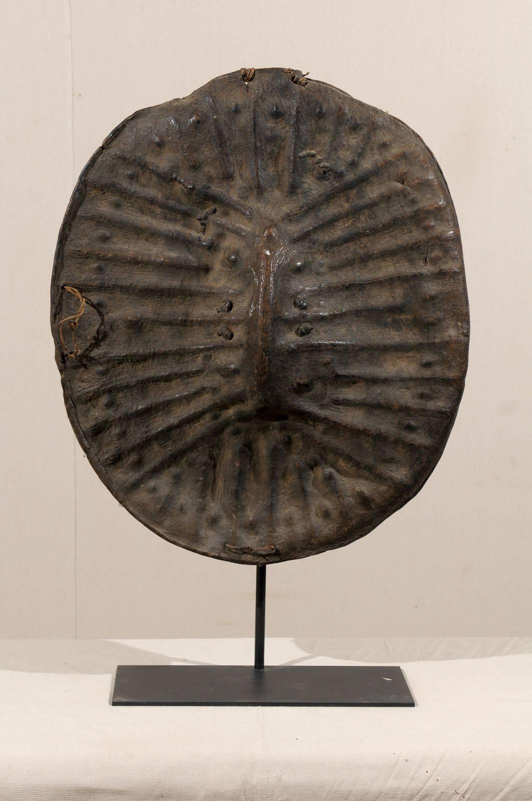 An Ethiopian leather shield on custom metal stand from early 20th century. The leather on this Ethiopian shield has been stretched and hammered to create a unique design. This item makes for a highly unique decorative accessory.