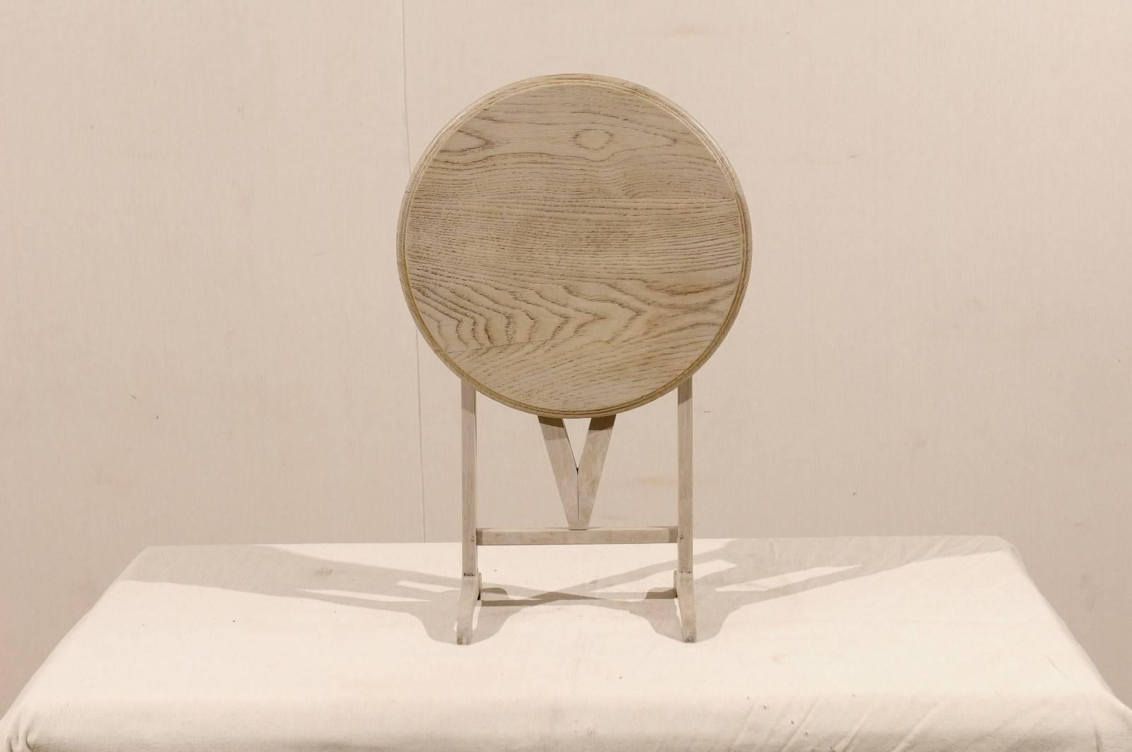 A Belgian petite sized wood folding table in a natural bleached finish from the mid 20th century. This adorable little table would be wonderful as an occasional table or a drinks table. The general color is a grey.