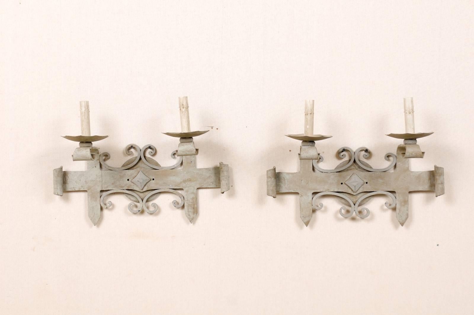 A pair of French iron sconces from the mid-20th century. Each of these French vintage iron sconces is made of hammered metal and is finished in a soft blue-grey color. Each sconce features two-lights. A diamond shaped motif adorns the centre of each