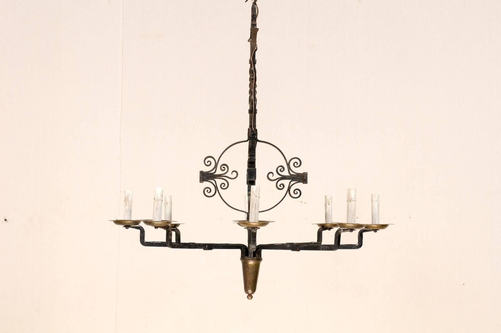 An Italian vintage circular eight-light wrought iron chandelier. This mid-20th century Italian iron chandelier features a central post with globe flanked with volutes on each side, leading to a twisted beam with a diamond shaped post top and hook.