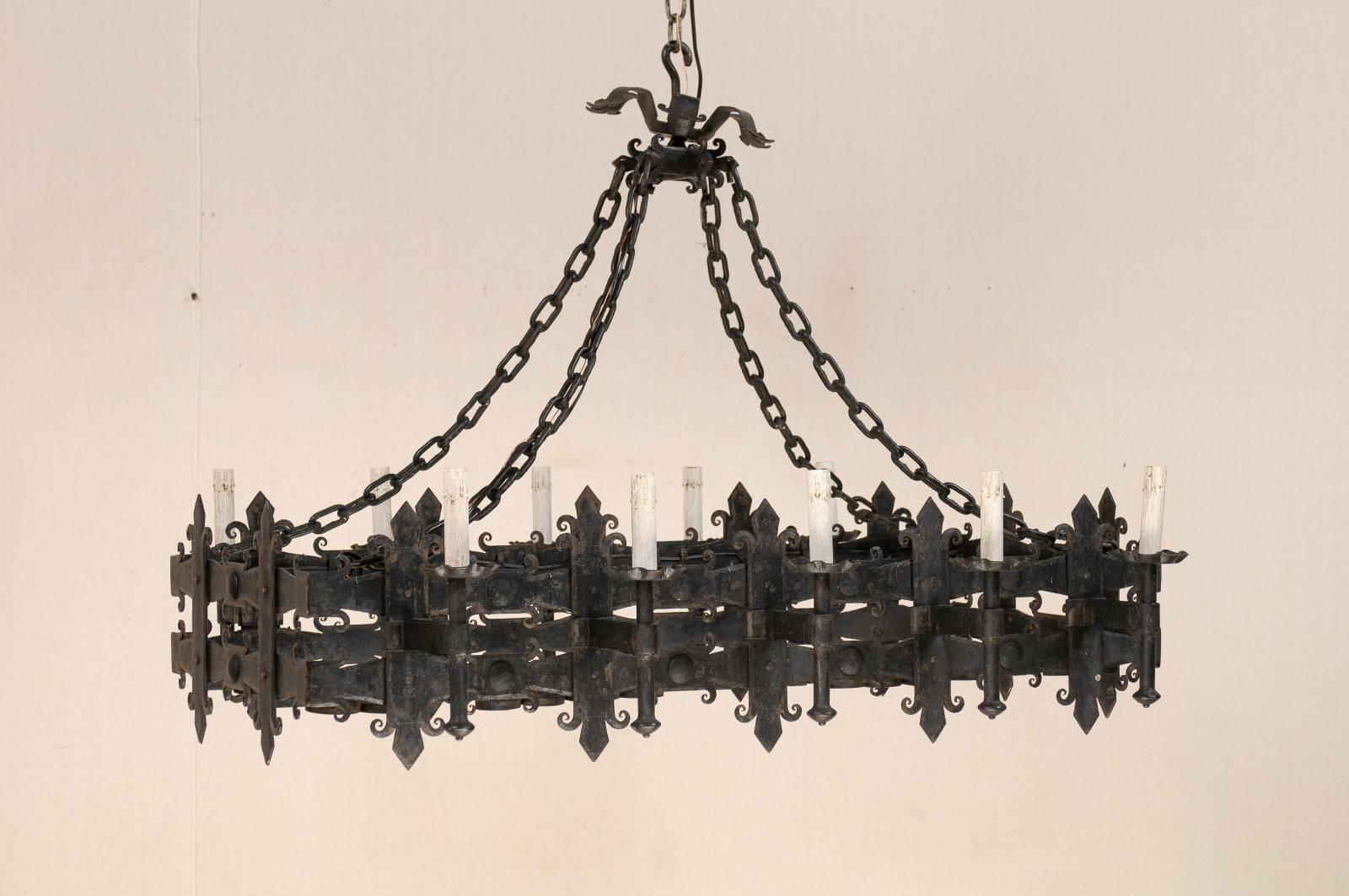 An Italian rectangular shaped forged iron ten-light vintage chandelier. This Italian mid-20th century chandelier features a double banded rectangular centre with vertical posts that have a fleur-de-lys design at each top and bottom. The underside of
