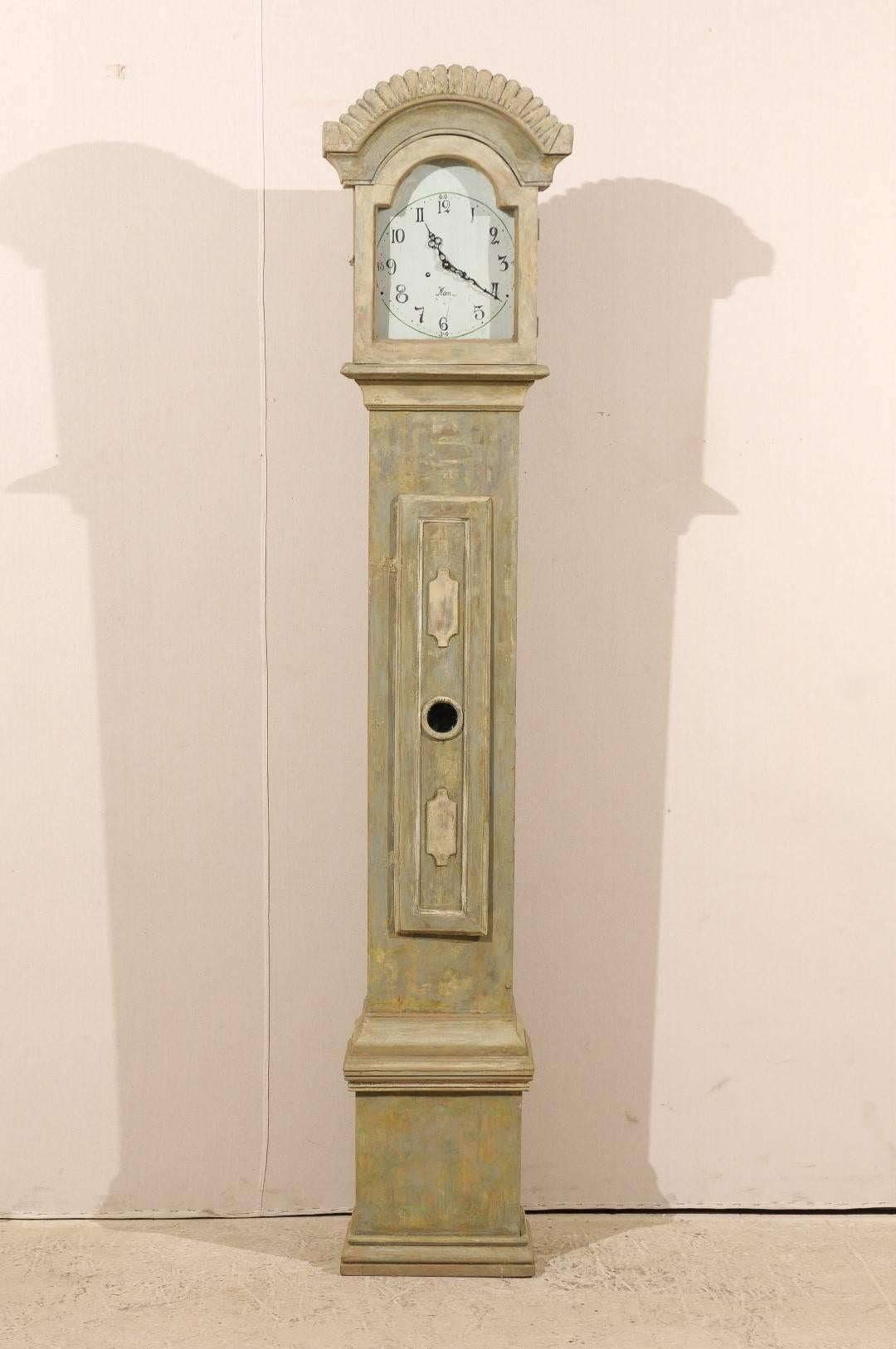 A 19th century Swedish clock. This clock may also be referred to as a Mora clock. This clock has a wonderful bonnet shaped crest arching along its top.   This bonnet is intricately carved and gives this piece a unique look. The arch at the top