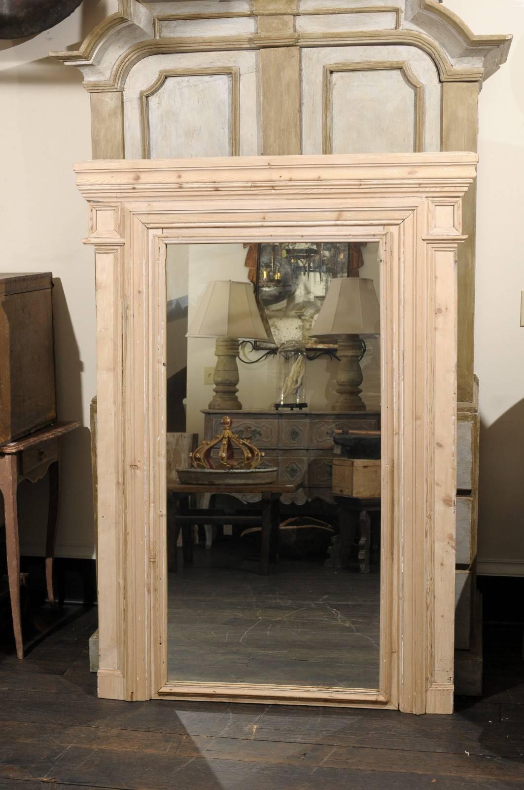 A French 19th century trumeau mirror with clean simple lines. This large French mirror features a natural wood finish with nice, visible wood grain throughout. This mirror has a very simple yet elegant look with its two nicely carved rectangles at