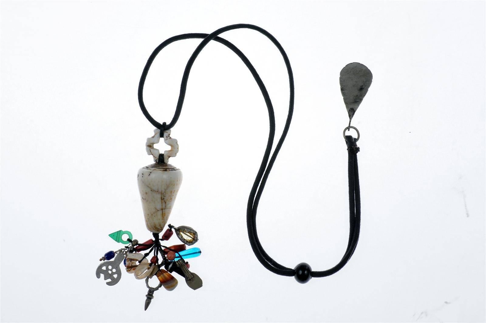 A custom-made necklace by Famous Moroccan Jeweler Chez Faouzi of Marrakech. Necklace features a conus shell along with a charming collection of Moroccan beads, shells and artifacts. Black cord necklace is adjustable to a maximum of 38.
