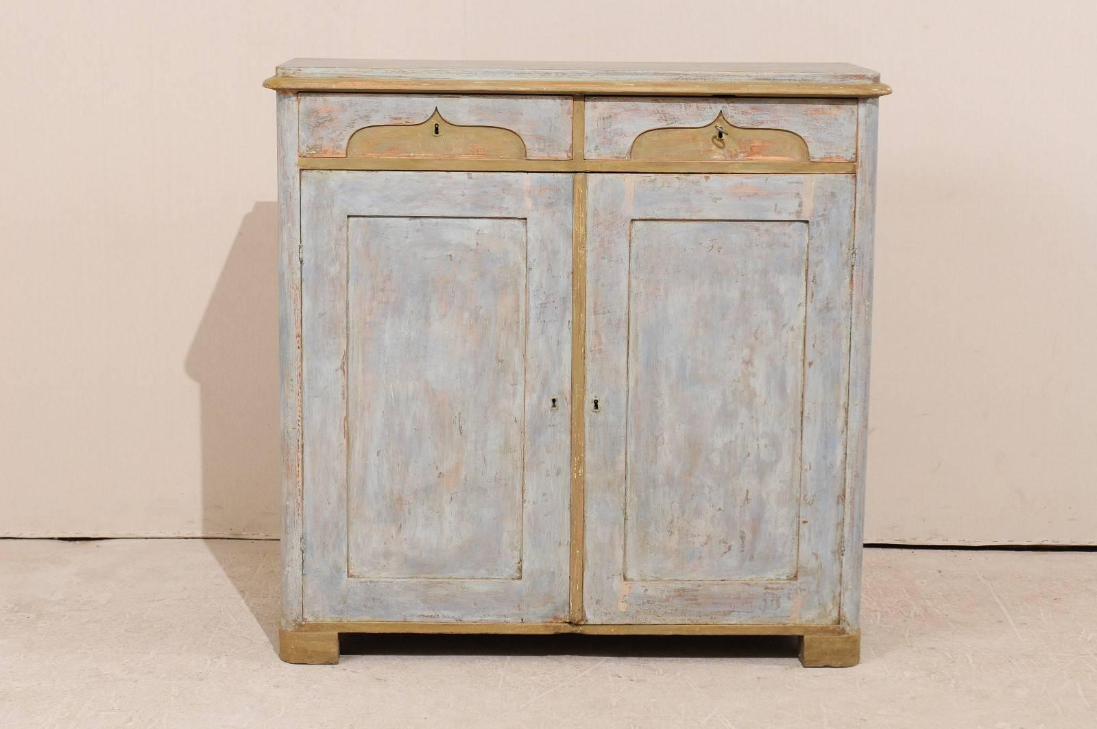 A 19th century, Swedish painted wood cabinet. This Swedish cabinet features two drawers over two doors with interior shelves. This Swedish cabinet, circa 1830, is raised on bracket wraparound feet. The two drawers are uniquely carved with an ogee