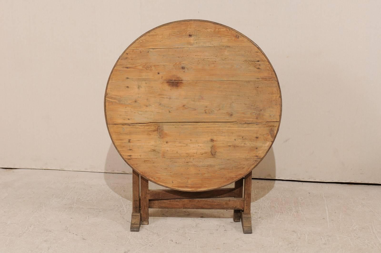 A French 19th century wine tasting table. In the typical tradition, this French wine tasting table features a tilt-top with gate legs. This rustic table has a natural finish and is nicely distressed. This French wine tasting table would work really