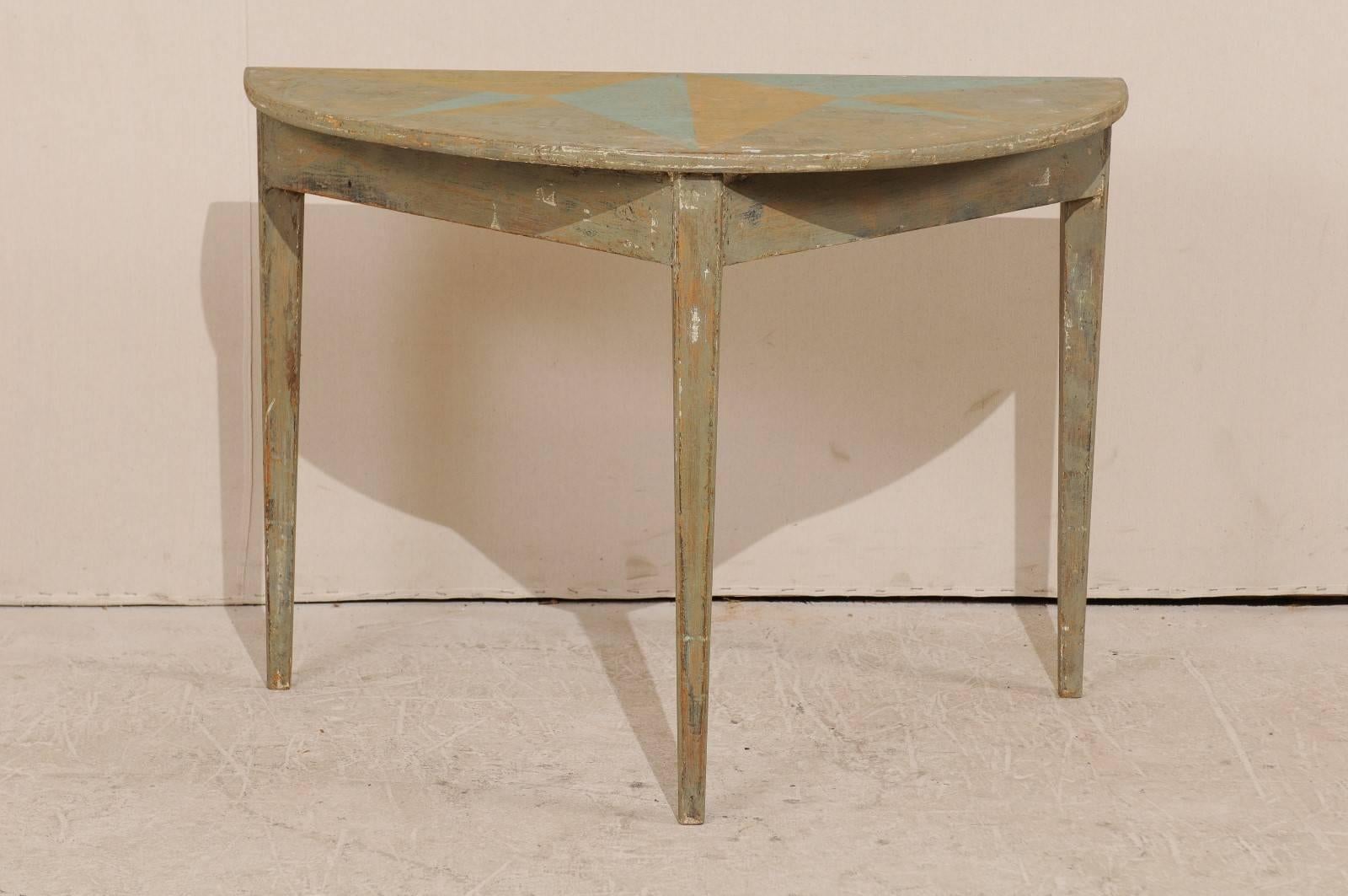 A 19th century Swedish painted wood demi lune table. This Swedish demi lune table features a semi-circular top over a triangular shaped apron. The top has a custom painted half-star design in a turquoise and cantaloupe and the overall table has a