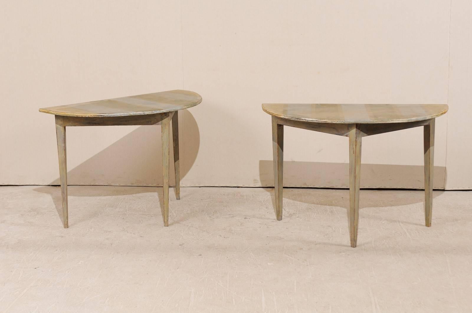 A Pair of 19th century Swedish painted wood demilune tables. This pair of Swedish demilune table features a semi-circular top over a triangular shaped apron. The top has a custom painted stripe design in a pale blue and green and the overall table