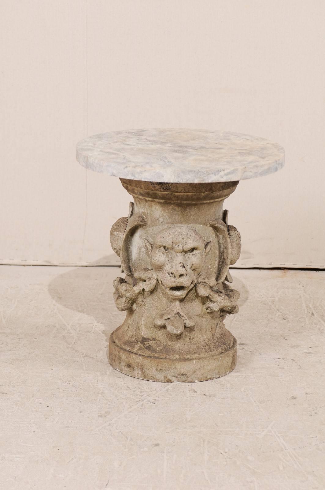 A French 19th century marble and carved limestone garden table. This charming garden table from France features a circular marble top over a carved limestone column base. Rustic yet refined, the carved limestone base depicts a pair of gargoyles at