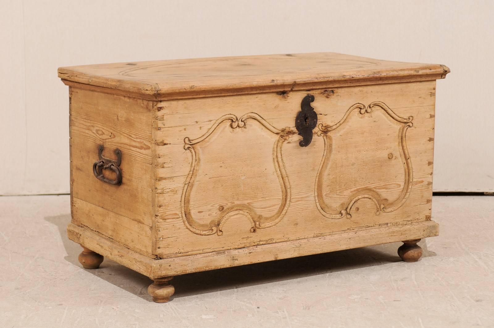 A Swedish 19th century wood coffer. This Swedish trunk from the 19th century features carved pine wood featuring an oval design at its top and two carved patterns on the front, reminiscent of a pair of shields. This pine chest has a natural wood