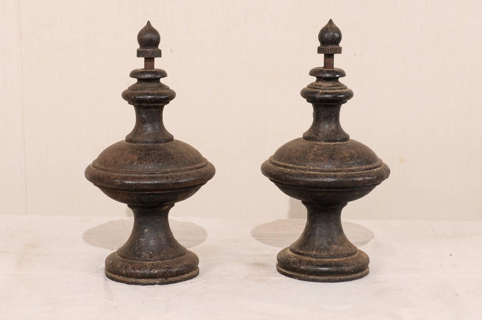 A pair of European cast iron finials from the 19th century. This pair of antique European finials are unique in form, have nicely shaped bodies, and great aged patina over dark cast iron. This pair of finials are functional as the balled tops lift