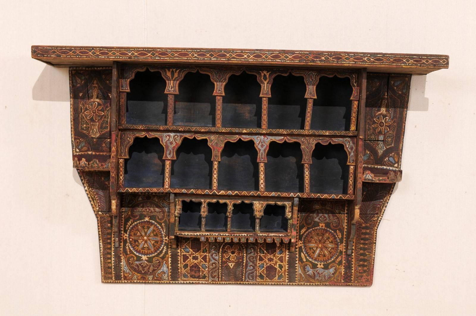 A mid-20th century Moroccan spice rack. This vintage Moroccan handmade and painted wood spice rack features a three terraced shelf design, and is elaborating adorn in various patterns, decorations, and colors typical of Moroccan art. Though this