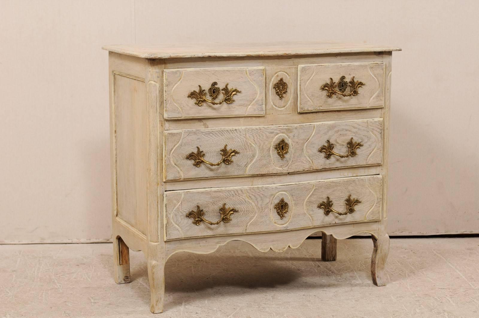A French mid-19th century wood chest. This 19th century French commode features two smaller drawers over two larger drawers. Each drawer features Rococo style hardware. The front and drawers are lightly carved, in a fluidly zig-zag down the front of