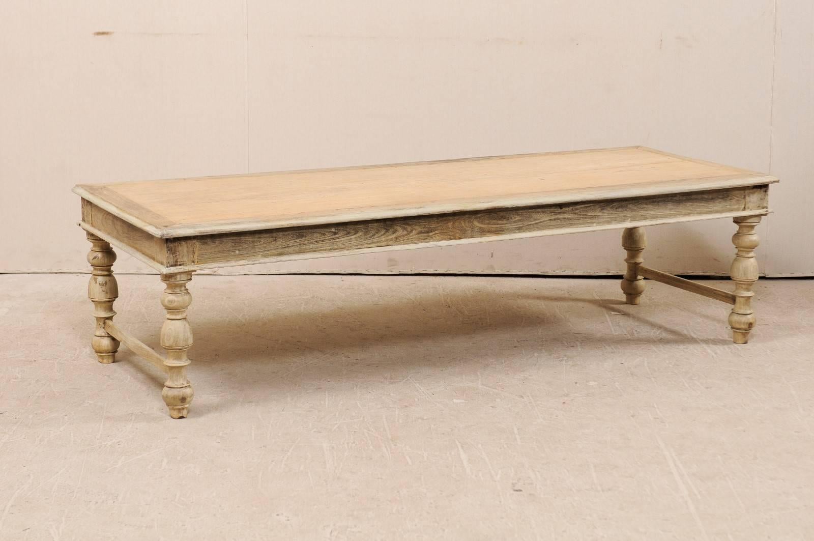 A Belgian mid-20th century wood coffee table. This Belgian coffee table of wood features a long, rectangular top and nicely turned legs. The skirt has nice, clean lines which mimic the top of this table. The legs are connected by a stretcher bar