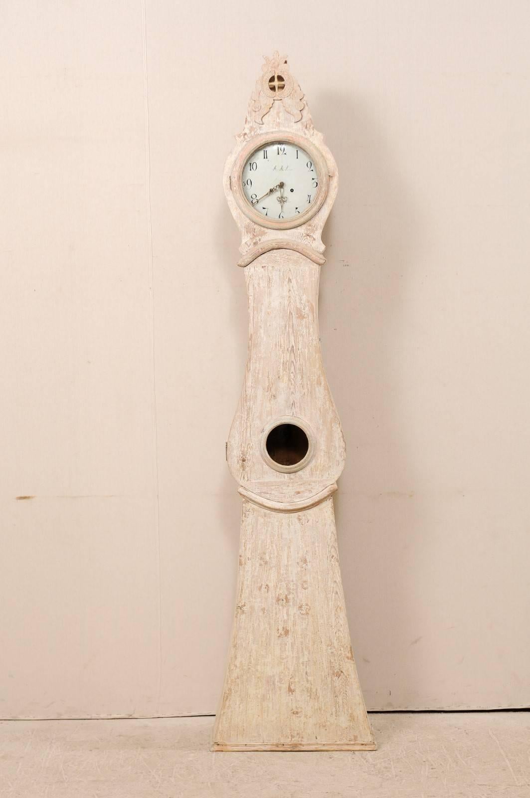 Une horloge suédoise en bois peint du 19ème siècle. Cette horloge suédoise du comté de Norrbotten, en Suède (région du Nord), présente un cimier exagéré et surélevé, sculpté en son centre d'un motif de quartiers percés, surmonté et entouré d'un