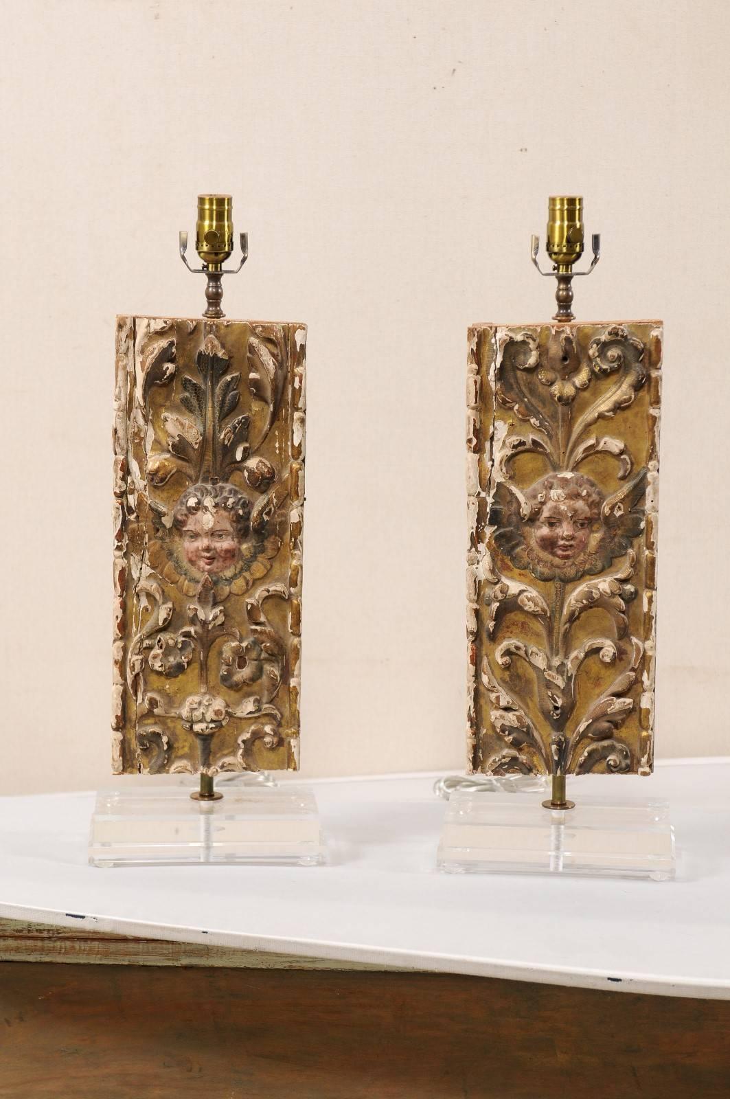 A pair of custom 18th century Italian fragment table lamps. This pair of Italian gilt and gesso over wood lamps feature a decor of rinceaux and acanthus leaves with the face of a putti at center. These fragments are raised on custom Lucite bases.