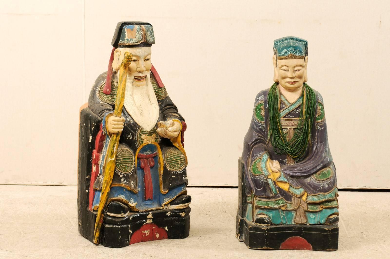 A pair of early 20th century Chinese carved and painted wood figures. These Chinese Emperor and Empress figures have been carved in great detail and feature their original paint which is nicely aged with lovely chipping. Male is holding staff and