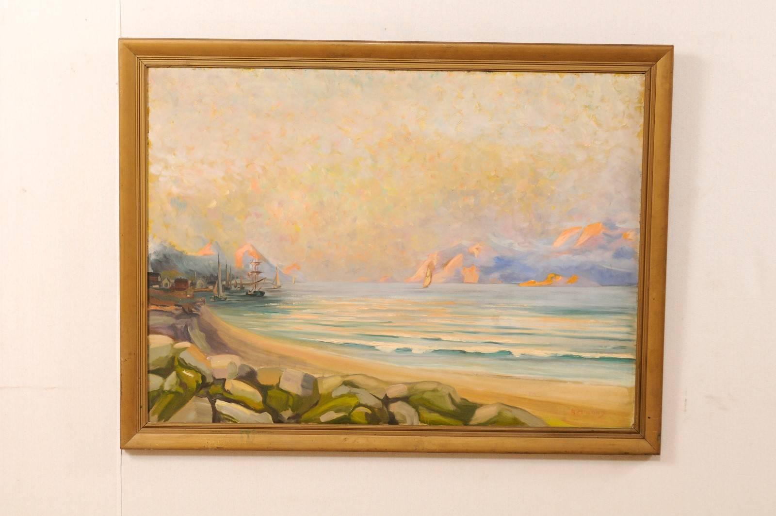 A vintage oil painting of the Swedish seaside. This mid-20th century Swedish landscape painting depicts the coast of a small fishing village, sailboats in the sea, with mountains in the distance. This piece features shades of blues, yellows, oranges