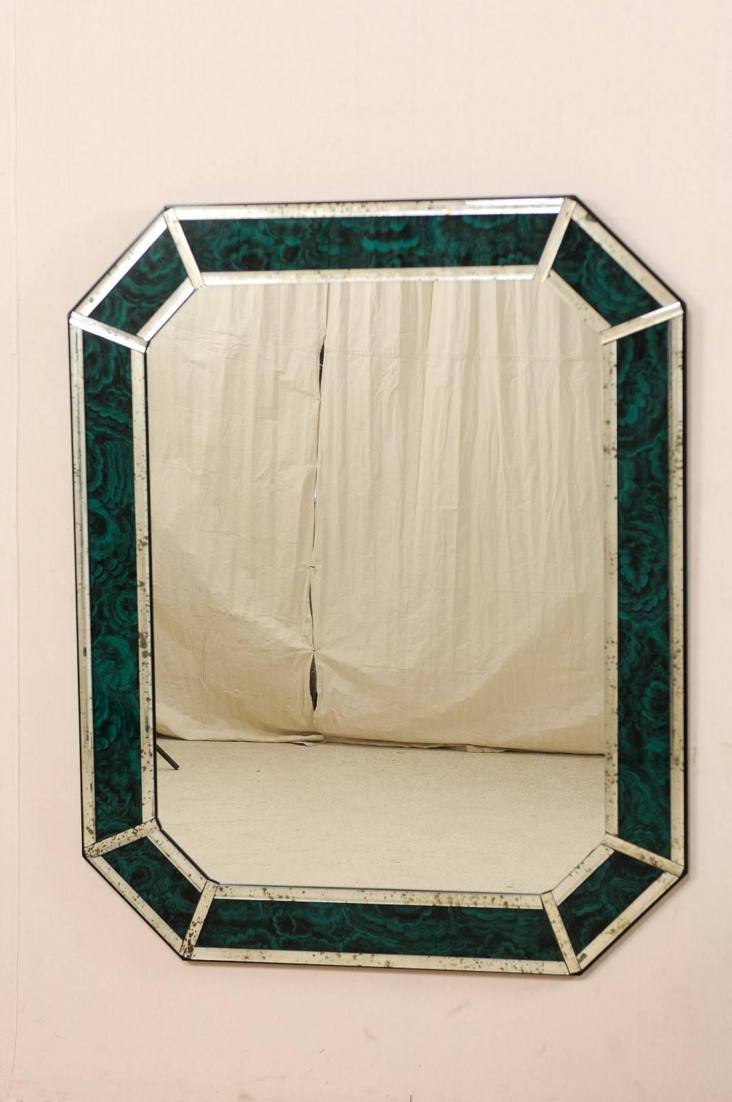 A large-sized, rectangular-octagon shaped mirror with accentuated malachite glass boarder. This American mirror features a clear center glass with a malachite glass surround, framed within antiqued glass sections. The malachite glass is a lovely
