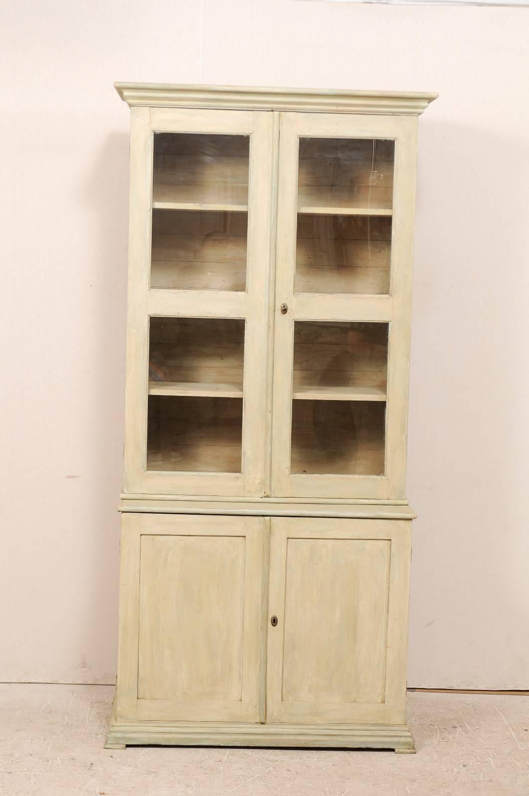 A 19th century Swedish painted wood bookcase and cabinet. This Swedish cabinet, circa 1830-1840, features two glass doors in the upper section over two enclosed bottom doors in the lower cabinet. There are interior shelves within the upper and lower