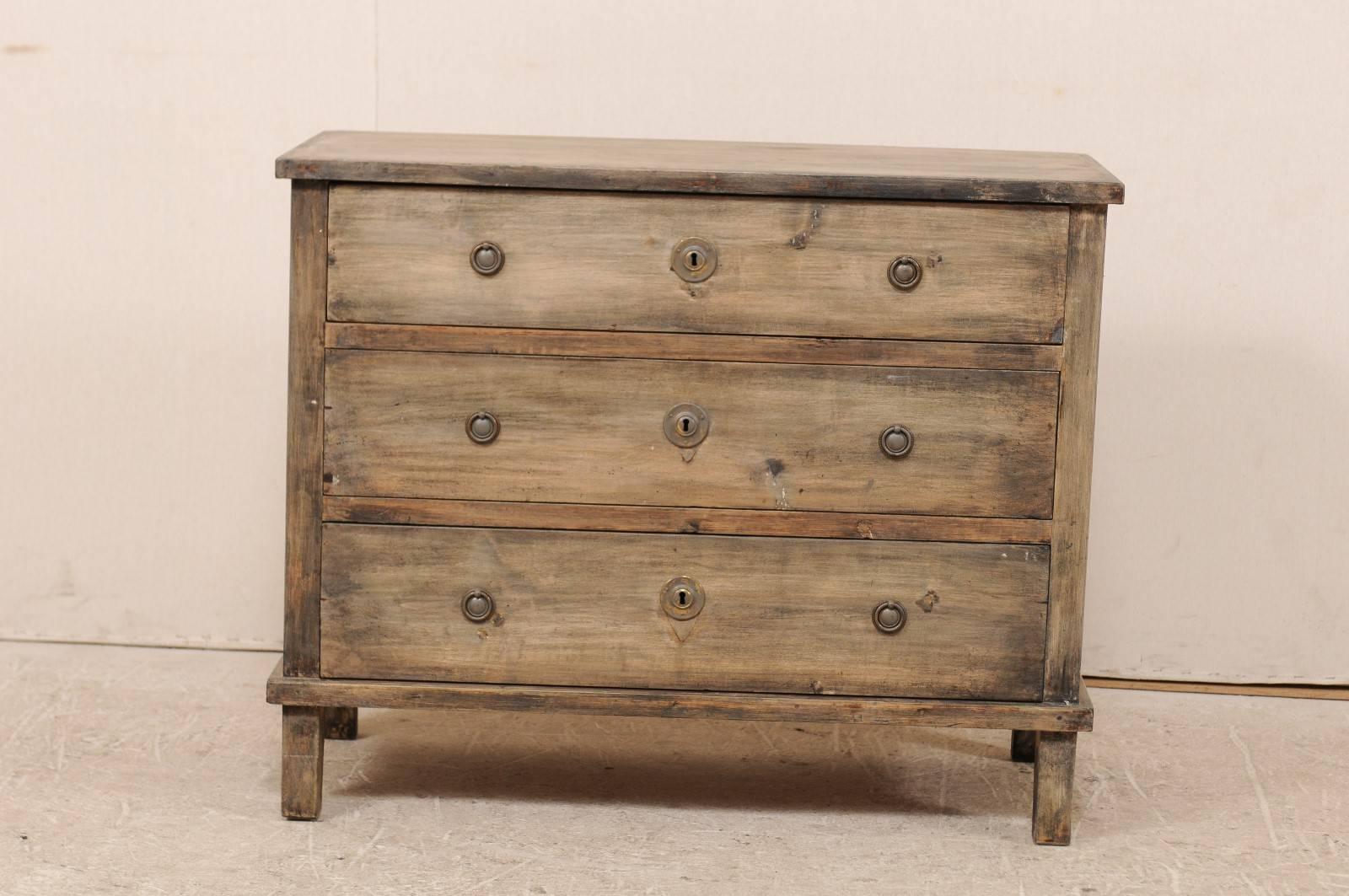 A Swedish, late 19th century wood chest. This Swedish three-drawer chest features nice clean lines, dovetail joins and is raised on tapered squared legs. The chest is washed in taupe, grey, black and warm brown tones. The drawers have circular mount