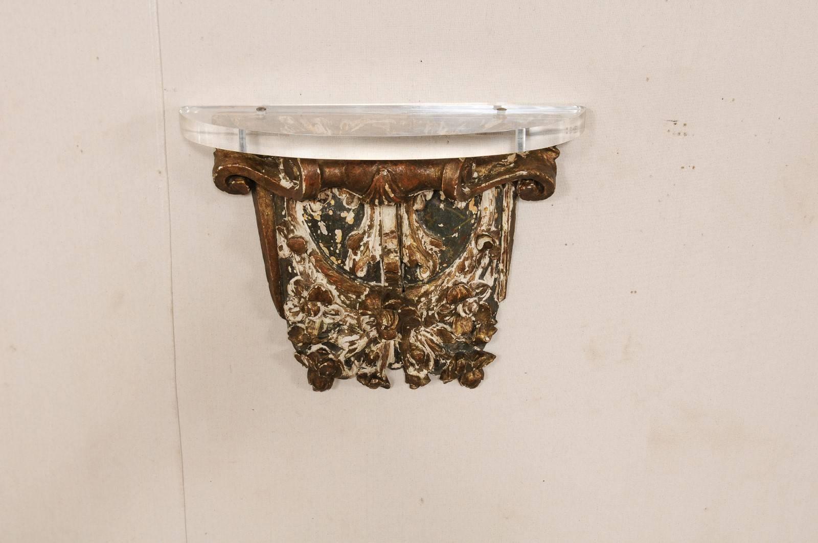 An early 19th century French architectural wood wall hanging fragment with Lucite shelf. This French architectural piece, from the early 19th century, has gilt over gesso and wood, and features hand-carved scroll and floral motif. The fragment has a