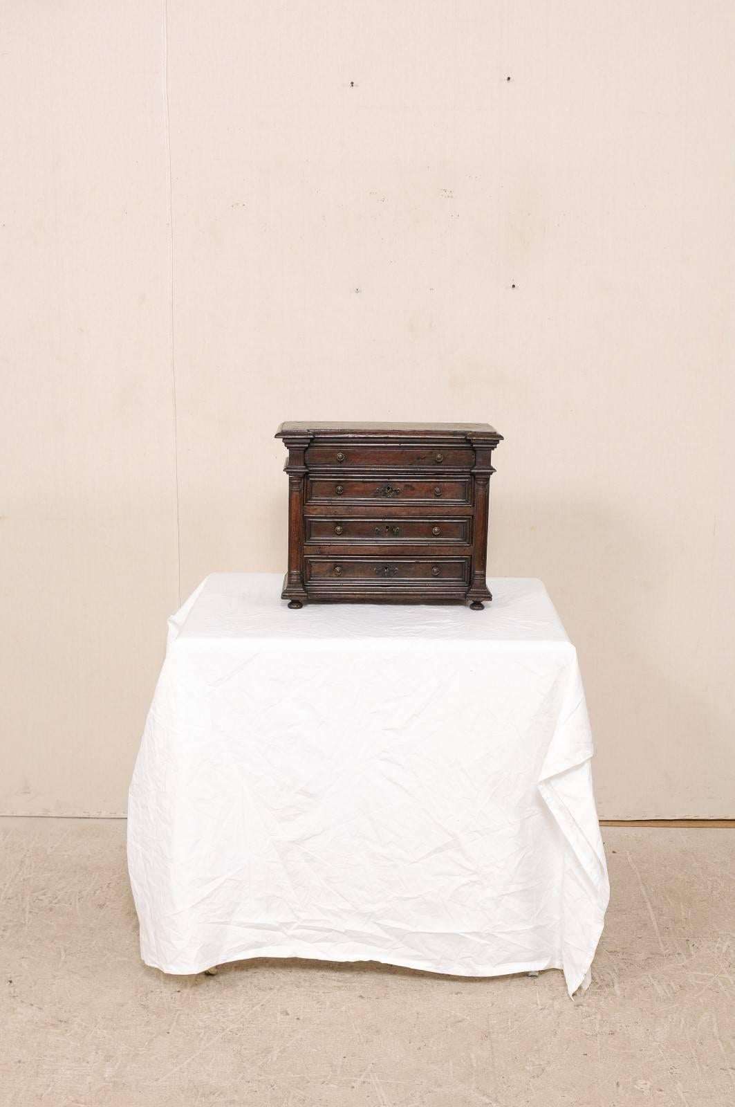 Eine kleine italienische Nussbaumtruhe aus dem frühen 18. Jahrhundert. Diese italienische Kommode mit vier Schubladen verfügt über geschnitzte Säulen, getäfelte Schubladen und Seiten und steht auf vier zierlichen Füßen. Diese Tischtruhe aus reichem