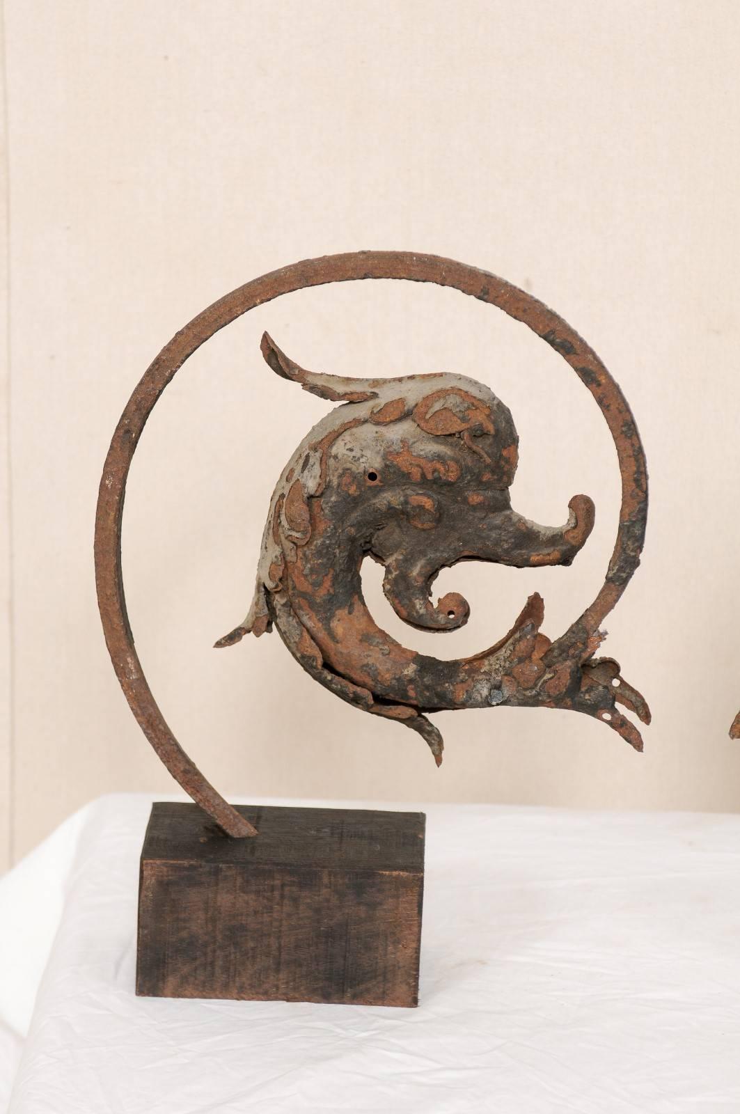 A pair of French, early 19th century mythological dolphin fish on stands. This is a pair of antique French architectural elements feature the heads of mythological dolphins which have been displayed on custom stands. The dolphins are iron with