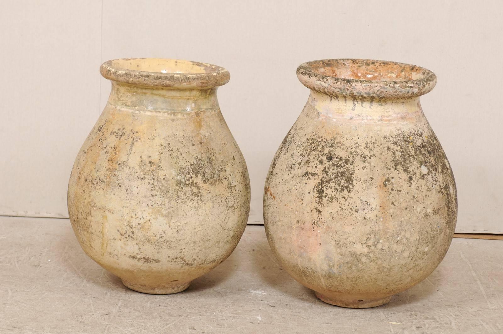 A pair of French 19th century Biot jars. This pair of antique French olive jars from Biot, France (a small potting village in the south of France) are made from terracotta with much of the original pale yellow glaze remaining about the neck and rim.