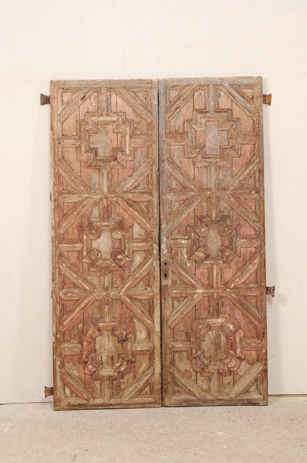A pair of 18th century Spanish wood carved doors. This pair of antique Spanish doors feature intricately carved and recess front panels on their front sides, with a geometric pattern. Their backsides are not carved, and have simple, clean lines. The