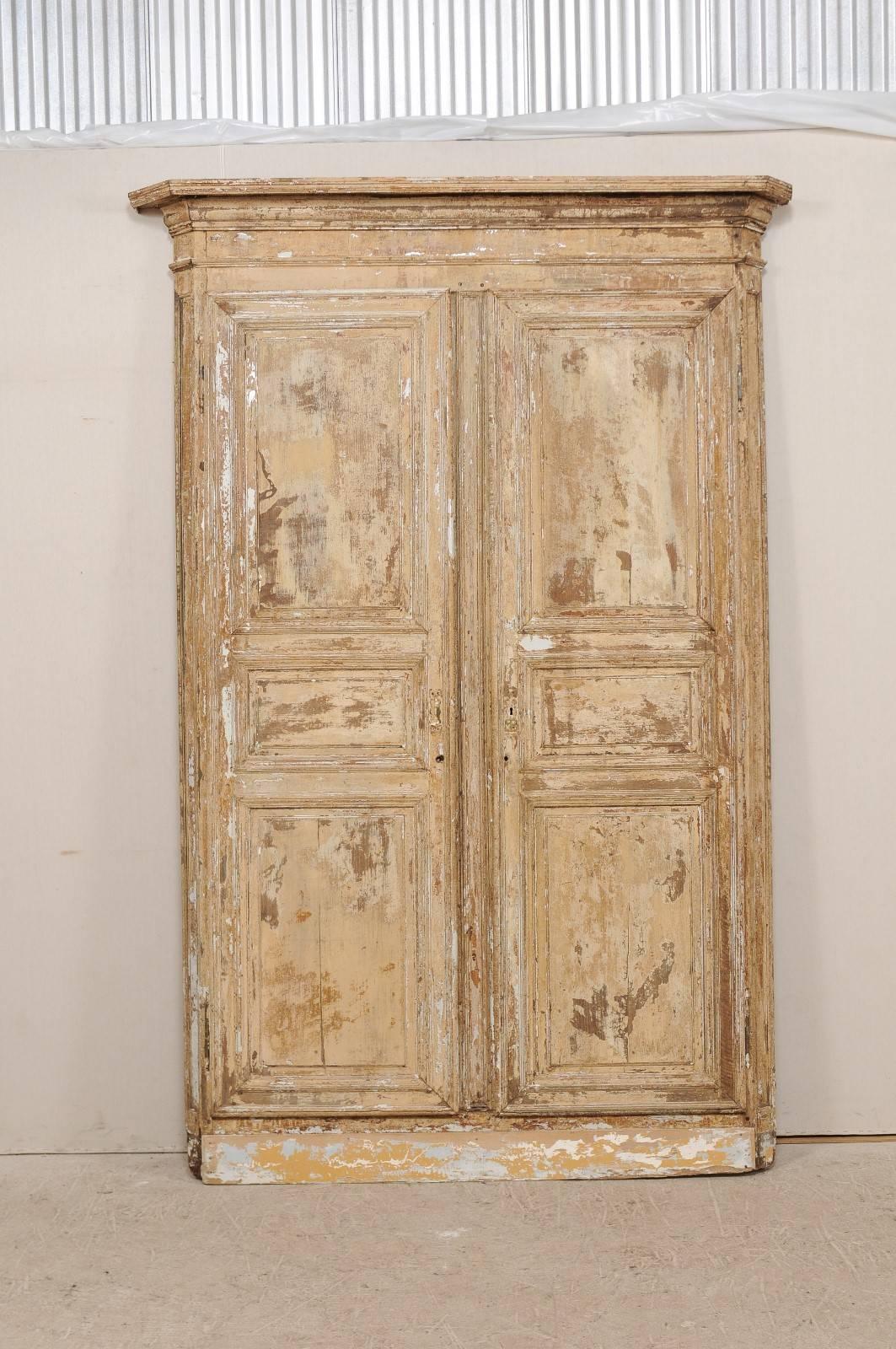 A pair of early 19th century Italian doors within their original carved wood casing. This fabulous piece consists of two antique Italian doors with their original casing. The surround or casing has an exquisite crosshead pediment that is heavily