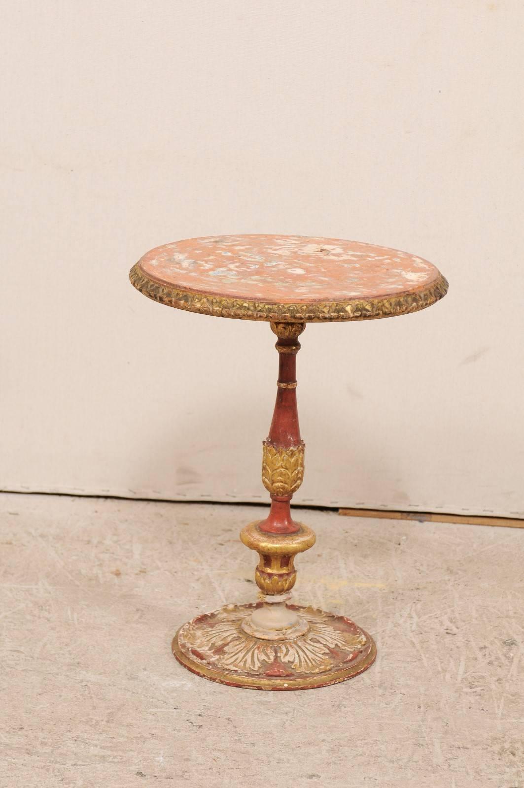 An Italian early 20th century round pedestal painted and carved wood table. This antique Italian round-shaped table features a beautifully carved acanthus leaf motif about the central column and floor base. The top is edged in an egg and dart styled