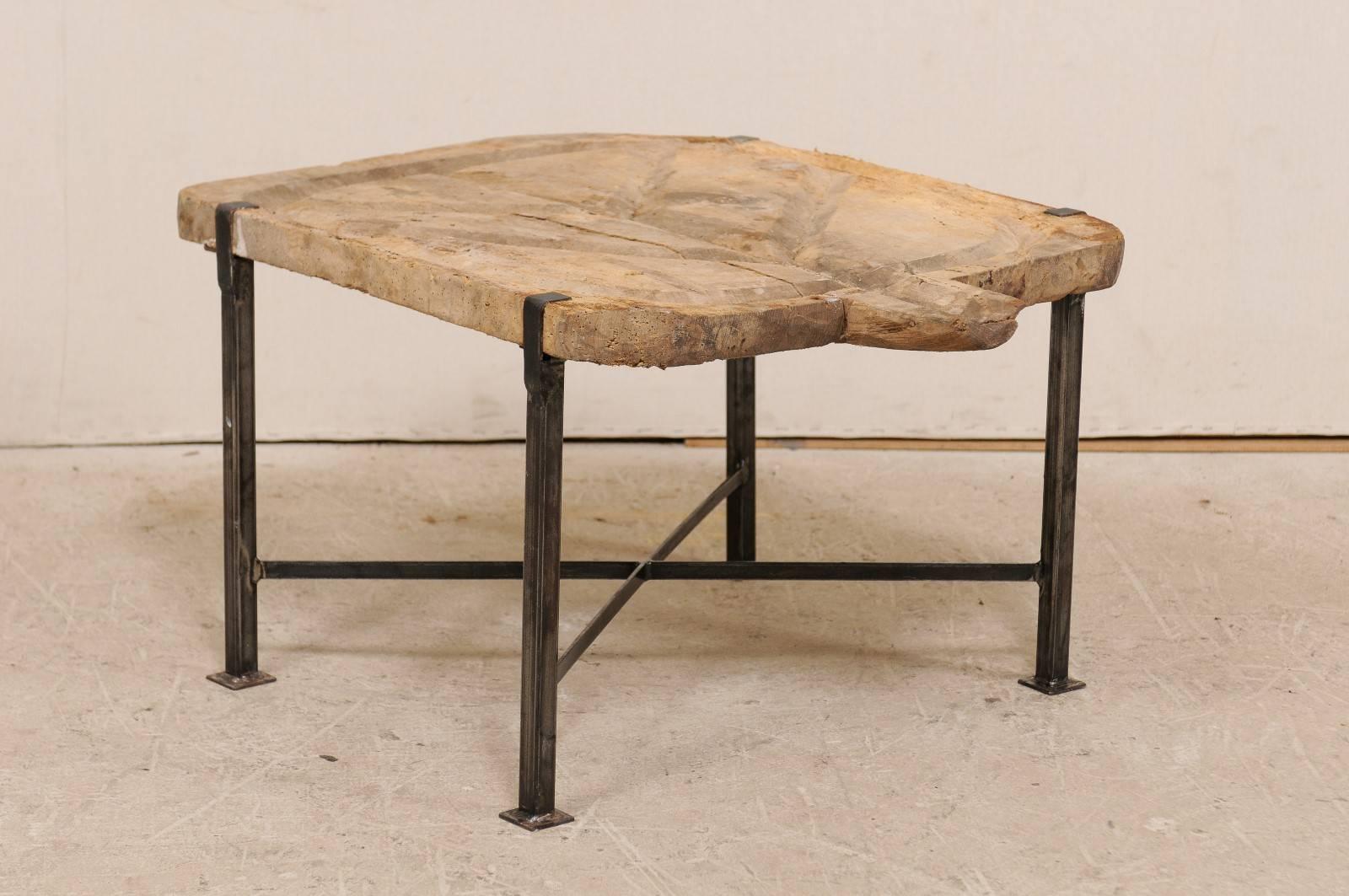 A custom Spanish wood and iron table. This coffee table has been fashioned from a 19th century Spanish cheese board as it's top which has been raised on a newer custom iron base. This piece features a natural wood top which has been hand carved with