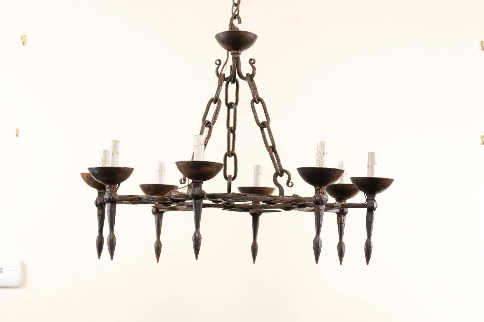 An elegant vintage French iron chandelier with eight lights. This French chandelier from the mid-20th century features an intricately designed center ring, adorn with hand-forged scroll work and eight decorative crossed bars that extend outward,