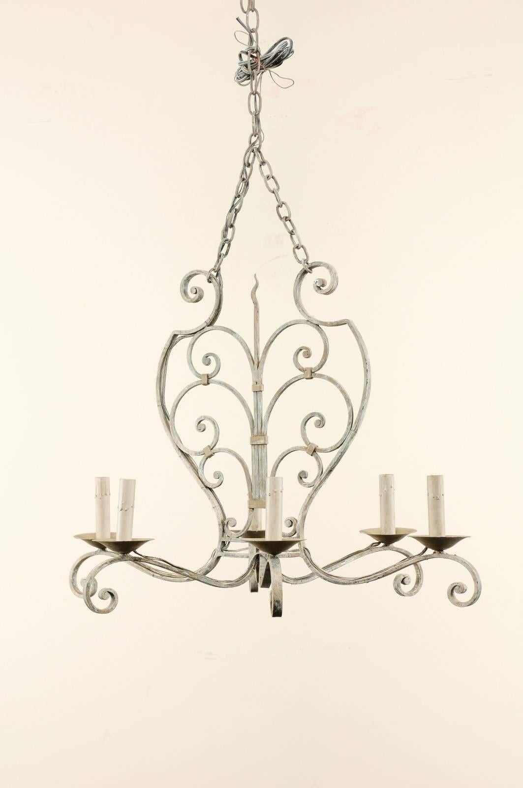A French midcentury painted iron chandelier. This vintage French six-light painted iron chandelier features a central two-dimensional body made of c-scrolls of various sizes joining at a central flame looking beam. This piece is very symmetrical and
